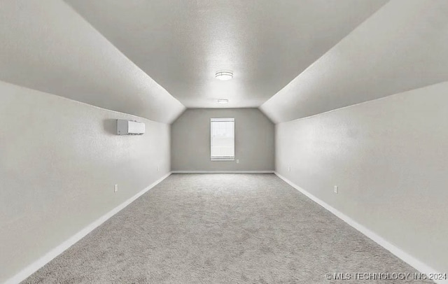 additional living space featuring a textured ceiling, carpet floors, and vaulted ceiling