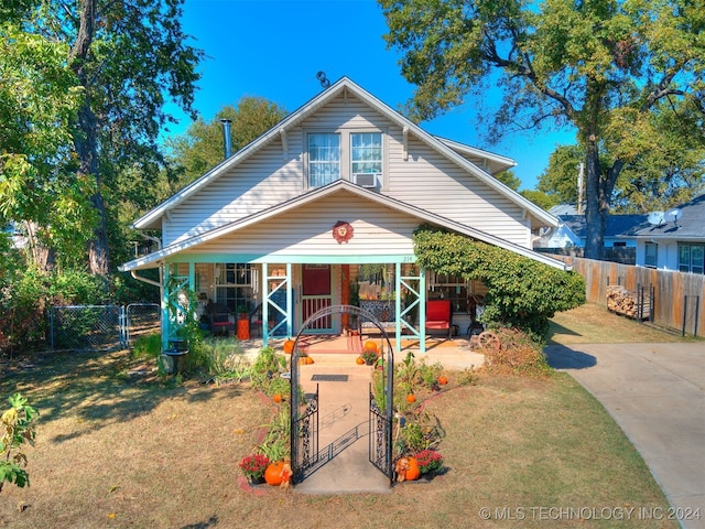 bungalow-style home with a front yard, cooling unit, and a porch