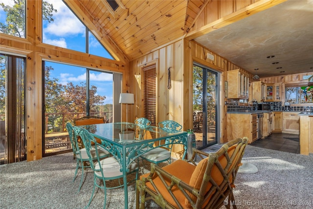 carpeted dining room featuring wooden walls, high vaulted ceiling, and wooden ceiling