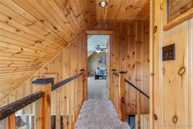 hall with wooden walls, carpet, and lofted ceiling