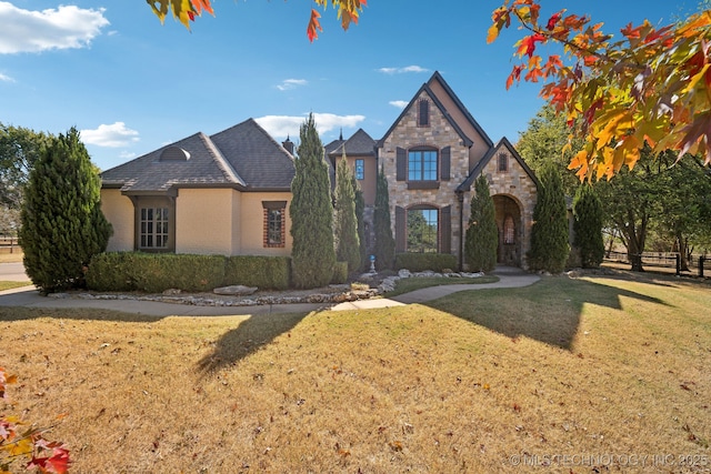 french provincial home featuring a front lawn, brick siding, and stone siding