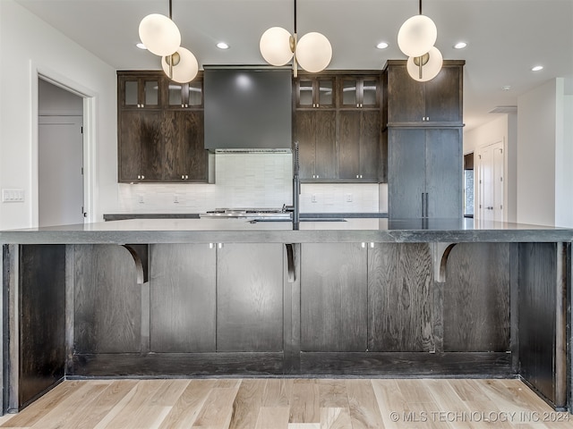 kitchen featuring dark brown cabinets, hanging light fixtures, ventilation hood, and light wood-type flooring