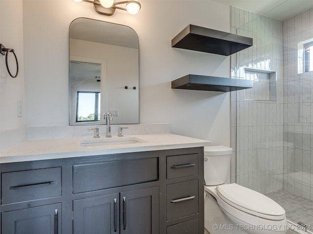 bathroom featuring vanity, toilet, and tiled shower