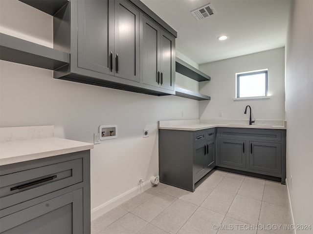 laundry area with sink, cabinets, electric dryer hookup, washer hookup, and light tile patterned floors