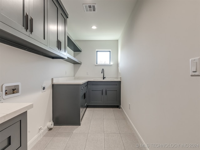 clothes washing area featuring hookup for a washing machine, hookup for an electric dryer, sink, light tile patterned flooring, and cabinets