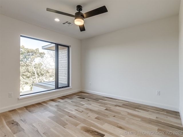 empty room with a wealth of natural light, light hardwood / wood-style floors, and ceiling fan