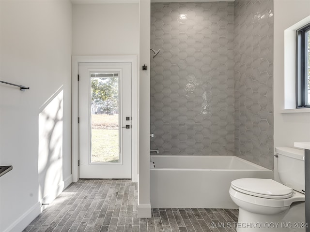 bathroom featuring toilet and tiled shower / bath