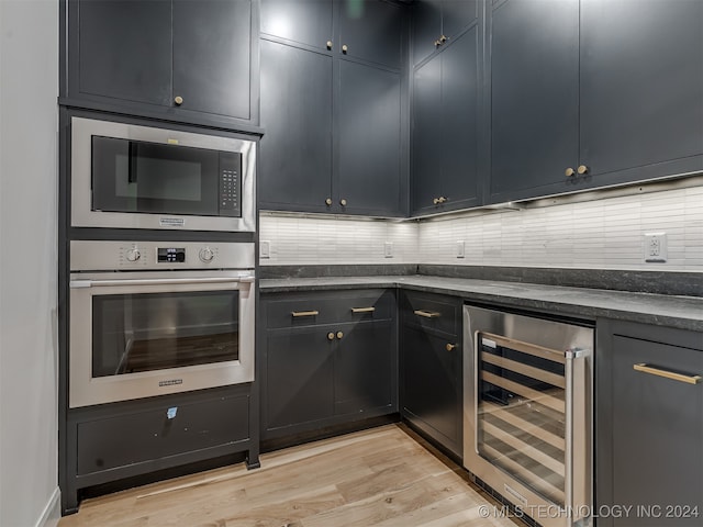 kitchen featuring appliances with stainless steel finishes, light hardwood / wood-style flooring, tasteful backsplash, and beverage cooler