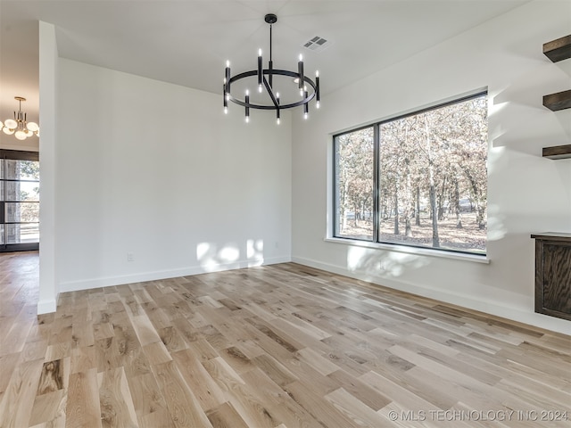 unfurnished dining area featuring an inviting chandelier and light wood-type flooring