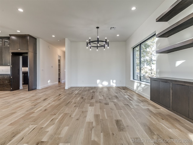 unfurnished dining area with a notable chandelier and light wood-type flooring