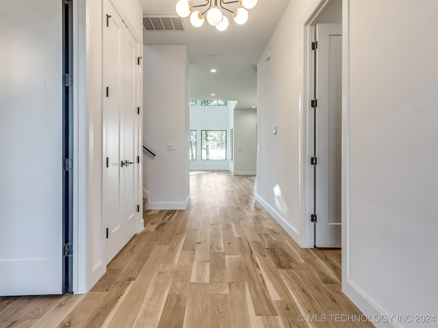 corridor featuring light hardwood / wood-style flooring and a chandelier