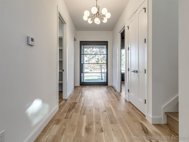 doorway to outside with light hardwood / wood-style floors and a notable chandelier