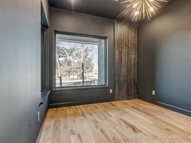 spare room with light hardwood / wood-style floors and a chandelier