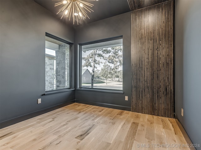 unfurnished room with wood-type flooring and an inviting chandelier