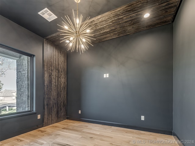 unfurnished room featuring an inviting chandelier and hardwood / wood-style flooring