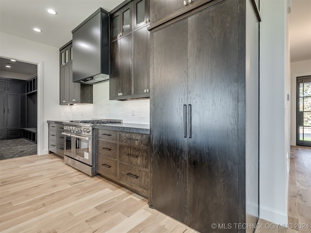 kitchen with light hardwood / wood-style floors, dark brown cabinetry, wall chimney range hood, and range with two ovens