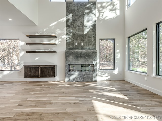 unfurnished living room featuring hardwood / wood-style floors, a fireplace, and a towering ceiling