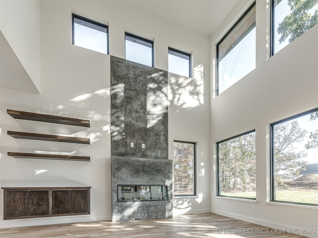 living room featuring light hardwood / wood-style flooring, a fireplace, and a towering ceiling