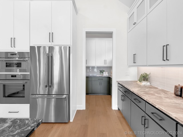 kitchen with gray cabinets, appliances with stainless steel finishes, white cabinetry, and dark stone countertops