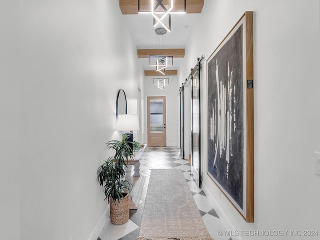 hall with a towering ceiling, a barn door, and light tile patterned flooring