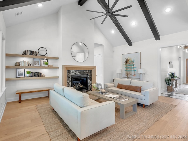 living room featuring light wood-type flooring, a fireplace, ceiling fan, beamed ceiling, and high vaulted ceiling