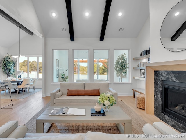 living room featuring light wood-type flooring, ceiling fan, beamed ceiling, high vaulted ceiling, and a premium fireplace