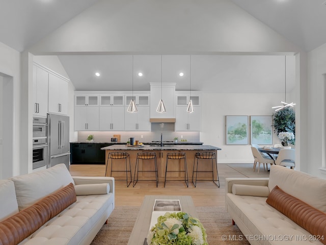 living room with light hardwood / wood-style floors, high vaulted ceiling, and sink