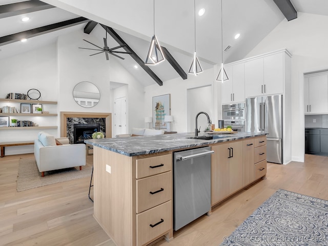 kitchen with beam ceiling, a kitchen island with sink, high vaulted ceiling, and stainless steel appliances