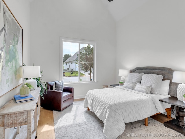 bedroom featuring high vaulted ceiling and light wood-type flooring