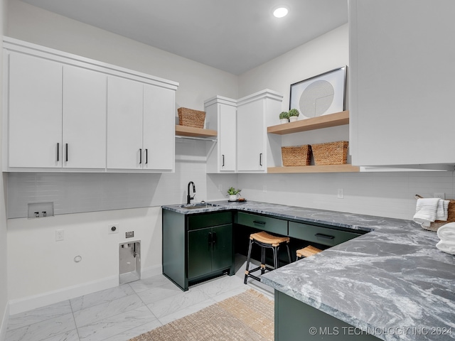 kitchen with white cabinetry, sink, and light stone counters