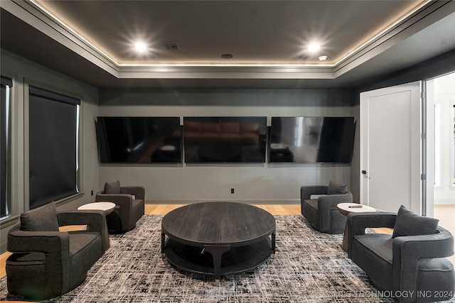 home theater room featuring a raised ceiling and hardwood / wood-style floors