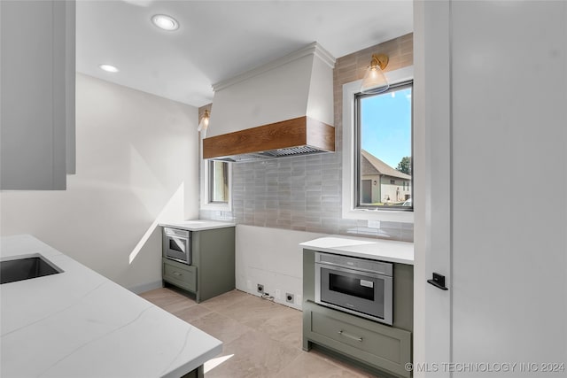 kitchen featuring oven, sink, premium range hood, and decorative backsplash