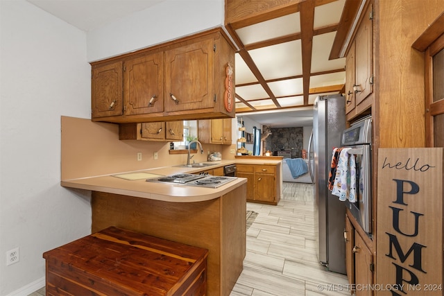 kitchen featuring appliances with stainless steel finishes, sink, light wood-type flooring, kitchen peninsula, and a kitchen breakfast bar