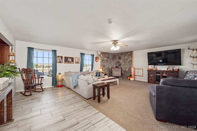 carpeted living room featuring a fireplace and ceiling fan