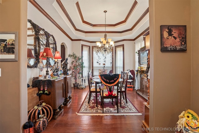 dining room featuring ornamental molding, an inviting chandelier, dark hardwood / wood-style floors, and a tray ceiling