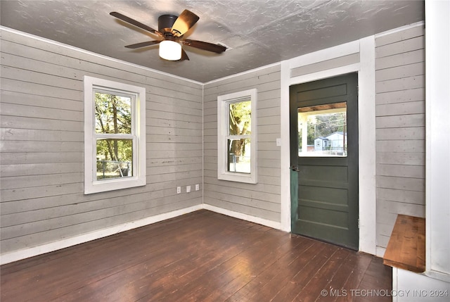 foyer featuring wooden walls, dark hardwood / wood-style floors, and ceiling fan