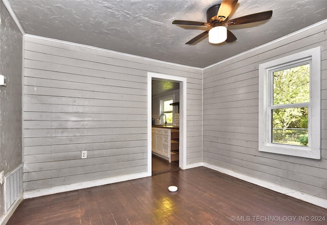 unfurnished room with wooden walls, ornamental molding, dark hardwood / wood-style floors, and ceiling fan