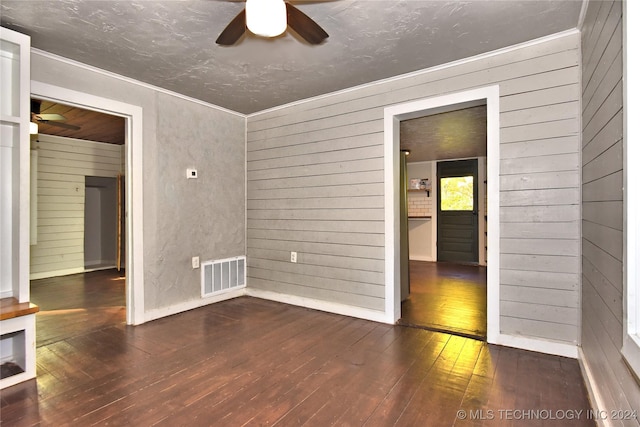 unfurnished room featuring dark wood-type flooring, ceiling fan, and wooden walls