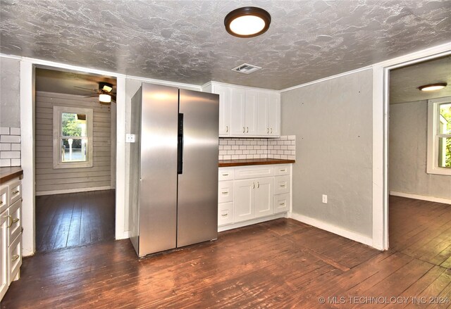 kitchen with white cabinetry, decorative backsplash, dark wood-type flooring, and stainless steel refrigerator