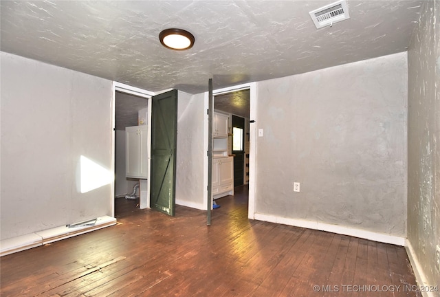 empty room featuring dark wood-type flooring and a textured ceiling