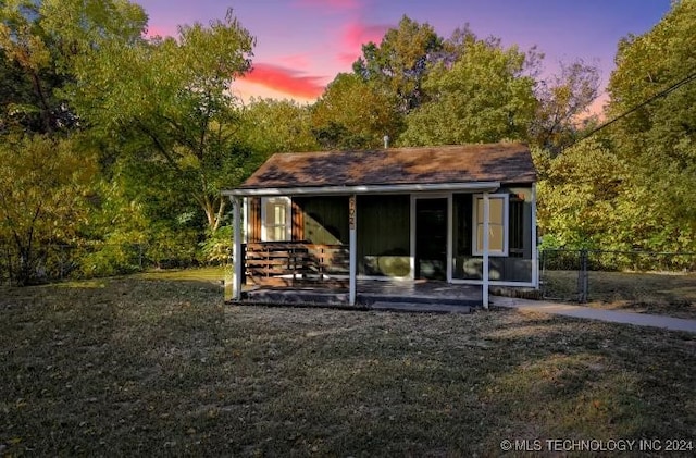 back house at dusk featuring a yard and a patio area