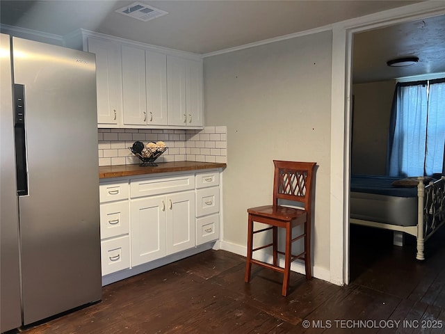 kitchen featuring white cabinetry, decorative backsplash, stainless steel fridge, and dark hardwood / wood-style floors