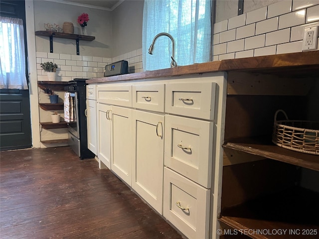 kitchen with white cabinets, decorative backsplash, ornamental molding, dark wood-type flooring, and stainless steel range oven