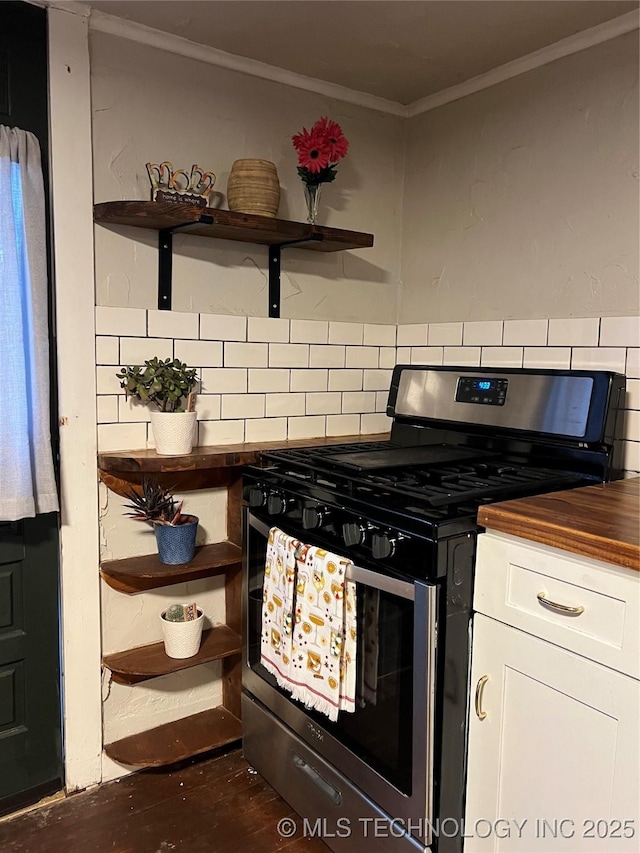 kitchen featuring wood counters, tasteful backsplash, white cabinetry, crown molding, and gas stove