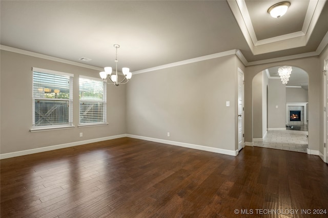 spare room with ornamental molding, an inviting chandelier, and dark hardwood / wood-style floors