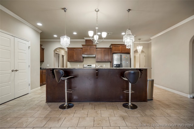 kitchen featuring a large island, stainless steel fridge, decorative light fixtures, and a breakfast bar area