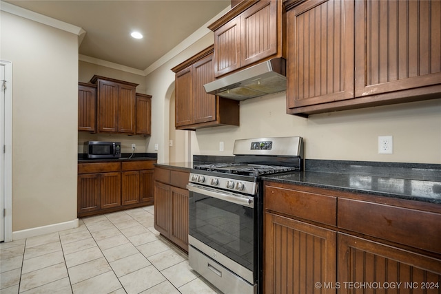 kitchen with crown molding, stainless steel appliances, light tile patterned floors, and dark stone counters