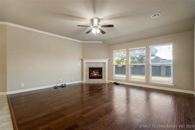 unfurnished living room with a tiled fireplace, hardwood / wood-style flooring, crown molding, and ceiling fan