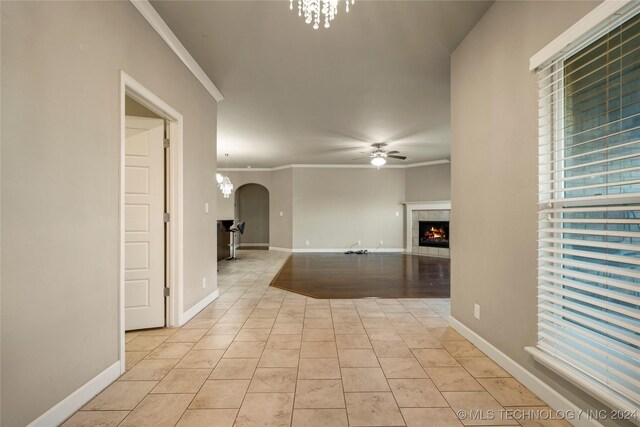 15410 E 87th St, Owasso, OK 74055 - empty room featuring arched walkways, ceiling fan, crown molding, a fireplace, and light tile patterned floors