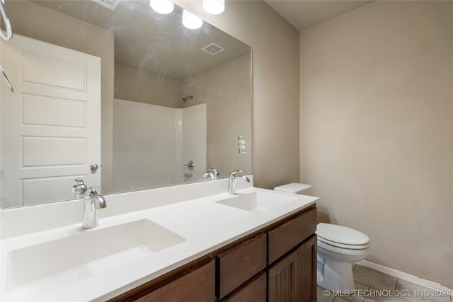 bathroom with toilet, vanity, and tile patterned flooring